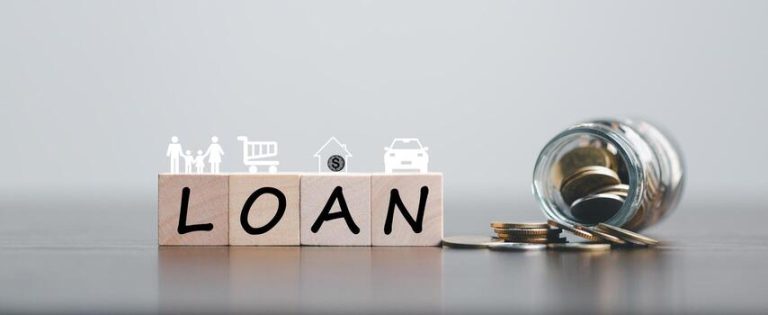 Four wooden blocks spell out the word LOAN. Above the letters are small white icons representing common uses for a loan: a family, a shopping cart, a house with a dollar sign, and a car. To the right, a glass jar is tipped over on its side, spilling a small pile of gold coins onto a dark surface. The image is conceptual, suggesting financial planning and a Loan Calculator.